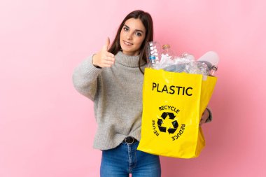 Pembe arka planda izole edilmiş plastik şişelerle dolu bir çanta tutan beyaz bir kadın iyi bir anlaşma için el sıkışıyor.