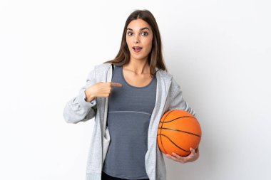 Basketbol oynayan genç bir kadın, beyaz arka planda izole edilmiş, şaşırmış bir yüz ifadesi var.