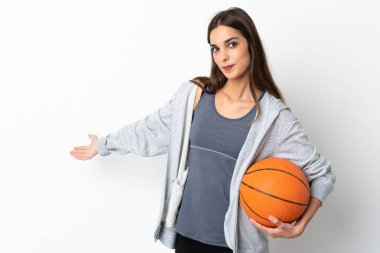 Basketbol oynayan genç bir kadın beyaz arka planda soyutlanmış, davet edilmek için ellerini yana uzatıyor.