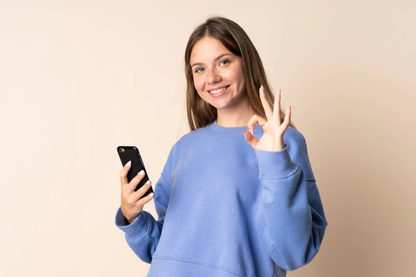 Jovem Lituana Usando Telefone Celular Isolado Fundo Bege Mostrando Sinal — Fotografia de Stock