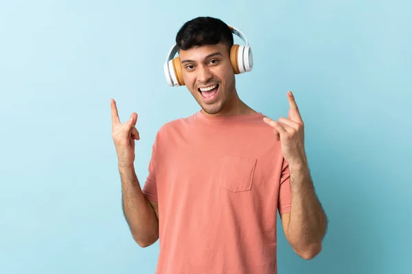 Jovem Colombiano Isolado Fundo Azul Ouvindo Música Fazendo Gesto Rock — Fotografia de Stock