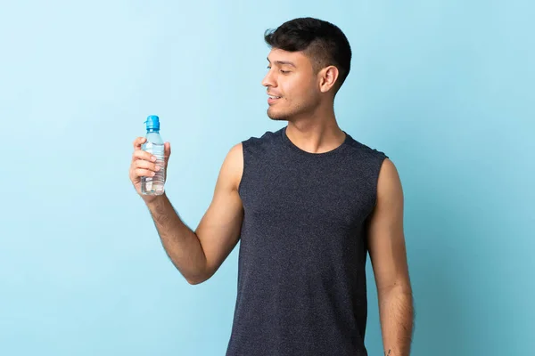 Joven Colombiano Aislado Sobre Fondo Azul Con Botella Agua Deportiva —  Fotos de Stock