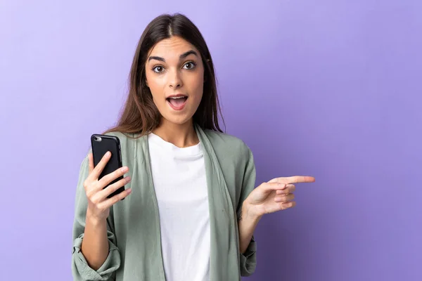 Молодая Белая Женщина Используя Мобильный Телефон Изолирован Фиолетовом Фоне Удивлен — стоковое фото