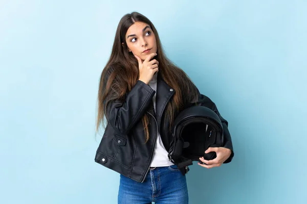 Jovem Caucasiana Segurando Capacete Motocicleta Isolado Fundo Azul Com Dúvidas — Fotografia de Stock