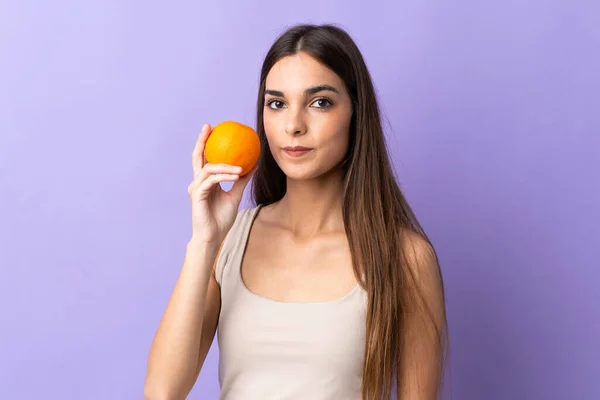Mujer Joven Caucásica Aislada Sobre Fondo Púrpura Sosteniendo Una Naranja — Foto de Stock