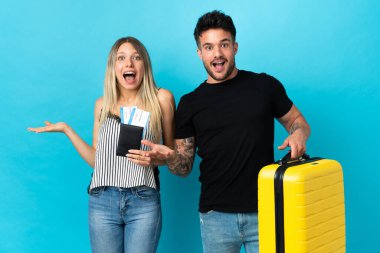 Genç beyaz çift mavi arka planda yalnız seyahat edecek. Şaşırmış ve şok olmuş bir yüz ifadesi var.