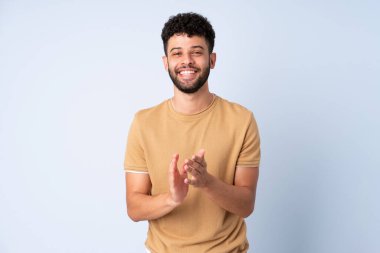 Genç Faslı bir adam mavi arka planda izole edilmiş bir konferansta sunumdan sonra alkışlıyor.