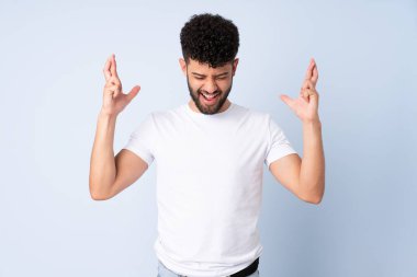 Faslı genç bir adam mavi arka planda izole edilmiş ve şans diliyor.