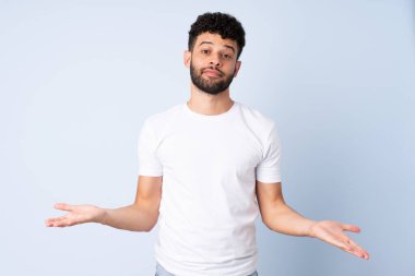 Genç Faslı adamın mavi arka planda izole edilmiş şüpheleri var.