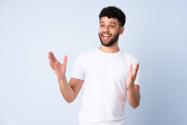 Молодой марокканский мужчина изолирован на синем фоне с удивительным выражением лица