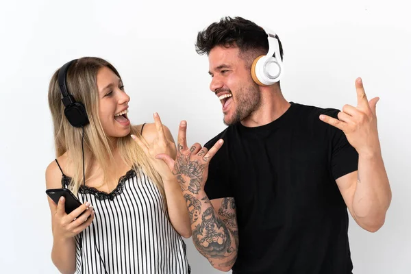 Jovem Casal Caucasiano Fundo Branco Ouvindo Música Fazendo Gesto Rock — Fotografia de Stock