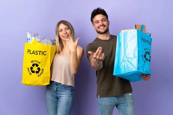 Joven Pareja Caucásica Reciclando Aislada Sobre Fondo Púrpura Invitando Venir —  Fotos de Stock