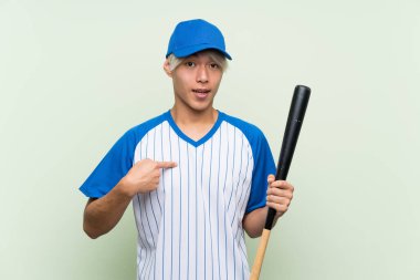Genç Asyalı beysbol oynayan, yalıtılmış yeşil arka planda, şaşırtıcı bir yüz ifadesi olan genç bir adam.