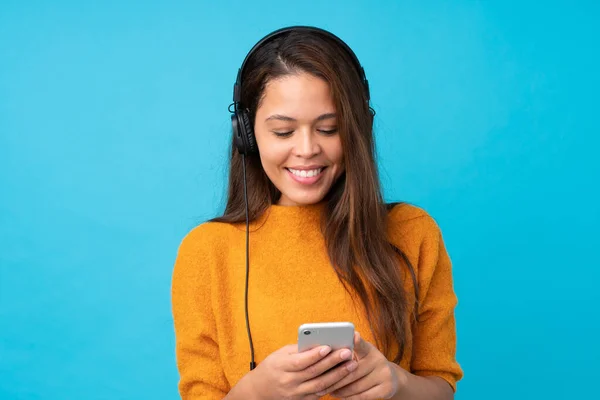 Mujer Joven Escuchando Música Con Móvil Sobre Una Pared Azul —  Fotos de Stock