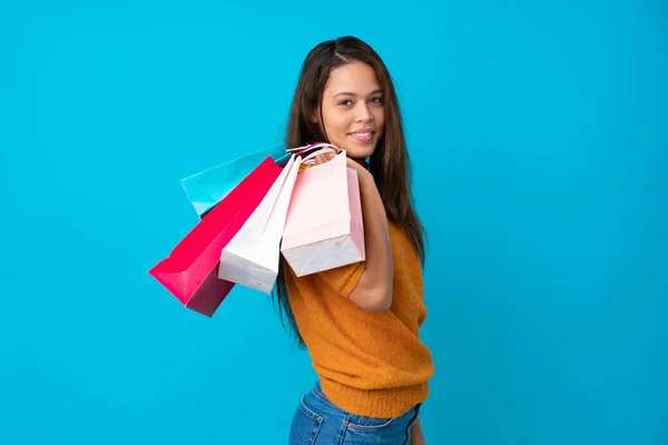 Joven Brasileña Sobre Fondo Azul Aislado Sosteniendo Bolsas Compras Sonriendo — Foto de Stock