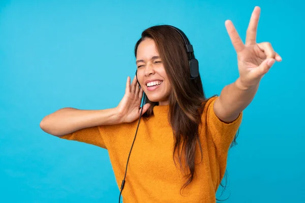 Mujer Joven Escuchando Música Sobre Una Pared Azul Aislada — Foto de Stock
