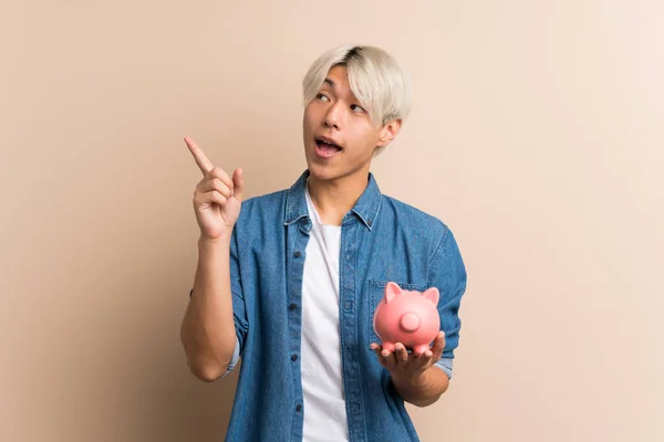 Jovem Ásia Homem Mais Isolado Fundo Segurando Grande Piggybank — Fotografia de Stock