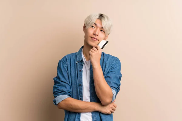 Junge Asiatische Mann Über Isolierten Hintergrund Mit Einer Kreditkarte — Stockfoto