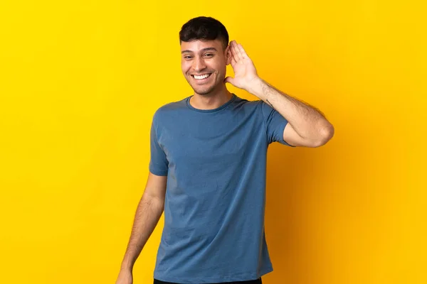 Junger Kolumbianischer Mann Isoliert Auf Gelbem Hintergrund Hört Etwas Indem — Stockfoto