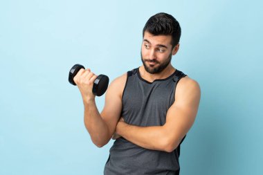 Sakallı genç sporcu hüzünlü bir ifadeyle ağırlık kaldırıyor.