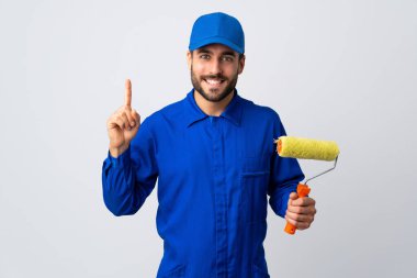 Beyaz arka planda izole edilmiş bir boya silindiri tutan ressam harika bir fikre işaret ediyor.