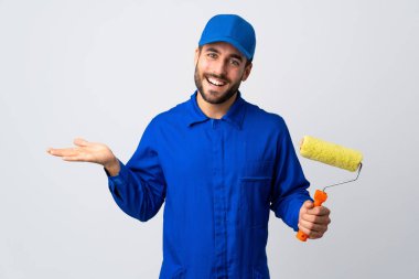 Ressam, beyaz arka planda izole edilmiş bir boya silindiri tutuyor. Avucunun içinde bir reklam koymak için görsel alan tutuyor.