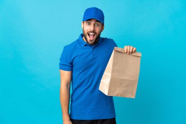 Mavi arka planda sakallı teslimatçı. Şaşırmış ve şok olmuş yüz ifadesi var.