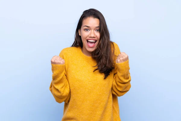 Joven Colombiana Con Suéter Sobre Fondo Azul Aislado Celebrando Una —  Fotos de Stock