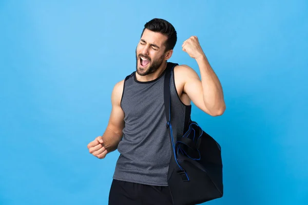 Joven Deportista Con Bolsa Deporte Aislada Sobre Fondo Azul Celebrando —  Fotos de Stock