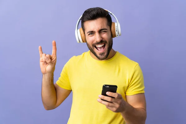 Joven Hombre Guapo Con Barba Aislada Sobre Fondo Púrpura Escuchando — Foto de Stock