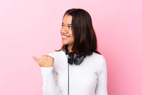 Mujer Joven Con Auriculares Sobre Una Pared Rosa Aislada Apuntando —  Fotos de Stock