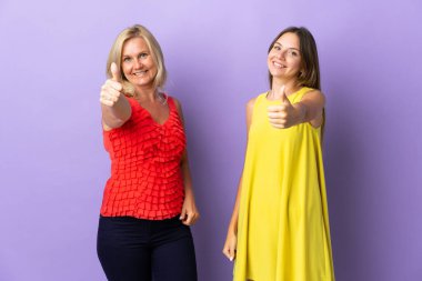 Anne ve kızı mor arka planda izole edilmiş. İyi bir şey olduğu için iyi bir jest yapıyorlar.