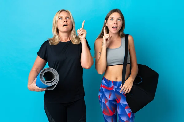 Mãe Filha Fazendo Ioga Isolado Fundo Azul Pensando Uma Ideia — Fotografia de Stock