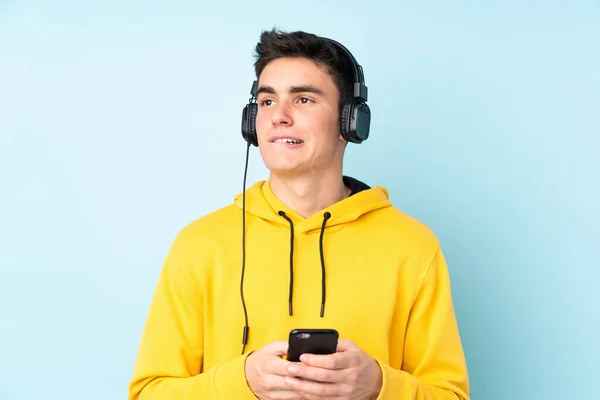 Tiener Kaukasische Man Geïsoleerd Paarse Achtergrond Luisteren Muziek Met Een — Stockfoto