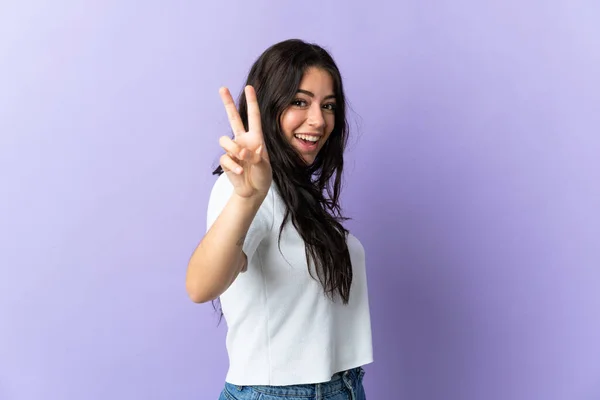 Jonge Kaukasische Vrouw Geïsoleerd Paarse Achtergrond Glimlachen Tonen Overwinning Teken — Stockfoto