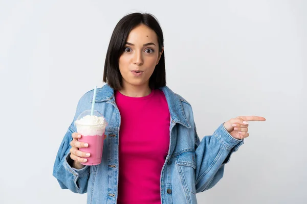 Jonge Vrouw Met Aardbei Milkshake Geïsoleerd Witte Achtergrond Verrast Wijzen — Stockfoto