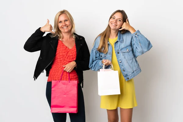 Mom and daughter buying some clothes isolated on white background making phone gesture. Call me back sign