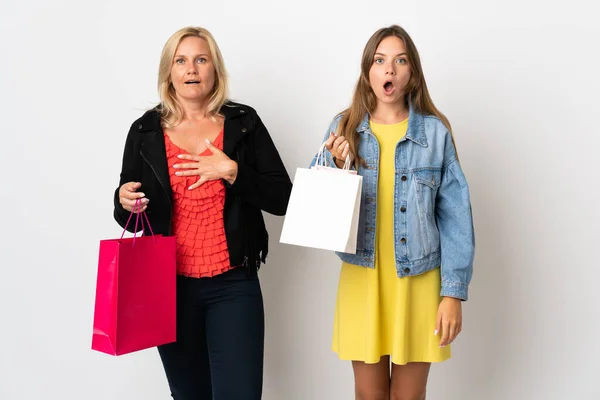 Mom and daughter buying some clothes isolated on white background with surprise and shocked facial expression