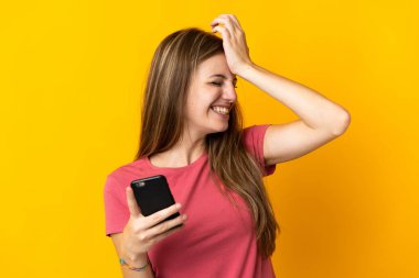 Sarı arka planda izole edilmiş cep telefonu kullanan genç kadın bir şey fark etti ve çözümü arıyor.