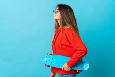 Mavi arka planda paten kayan beyaz bir kadın.