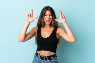 Genç beyaz kadın, mavi arka planda izole edilmiş ve şans diliyor.