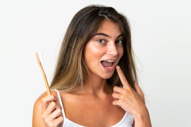 Beyaz arka planda diş fırçası ve mutlu bir ifadeyle izole edilmiş beyaz bir beyaz kadın.