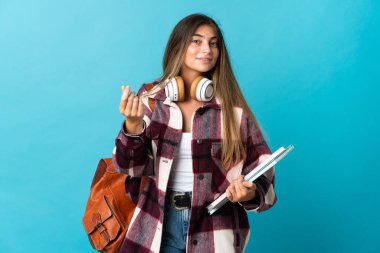 Genç bayan öğrenci mavi arka planda izole edilmiş para hareketi yapıyor.