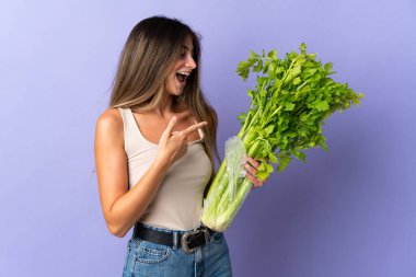 Elinde mor arka planda izole edilmiş bir kereviz tutan genç bir kadın.