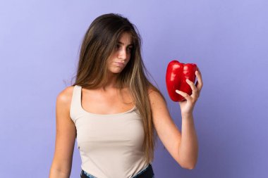 Mor arka planda karabiber tutan genç kadın üzgün bir ifadeyle izole edilmiş.