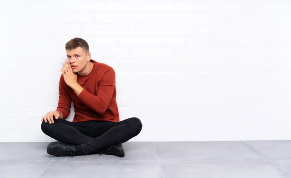 Mladý Pohledný Muž Sedí Podlaze Něco Šeptá — Stock fotografie