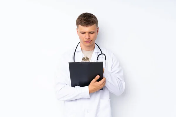 年轻英俊的男子 穿着医生的长袍 在一个文件夹里书写 背景是孤立的 白色的 — 图库照片