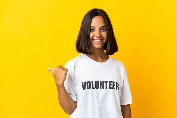 Mujer Joven Voluntaria Aislada Sobre Fondo Amarillo Apuntando Hacia Lado — Foto de Stock