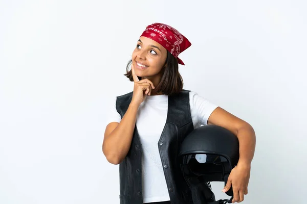 Young woman holding a motorcycle helmet isolated on white thinking an idea while looking up