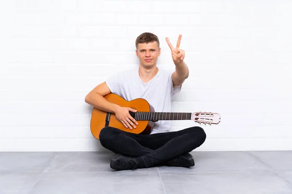 Ung Stilig Man Med Gitarr Leende Och Visar Segertecken — Stockfoto